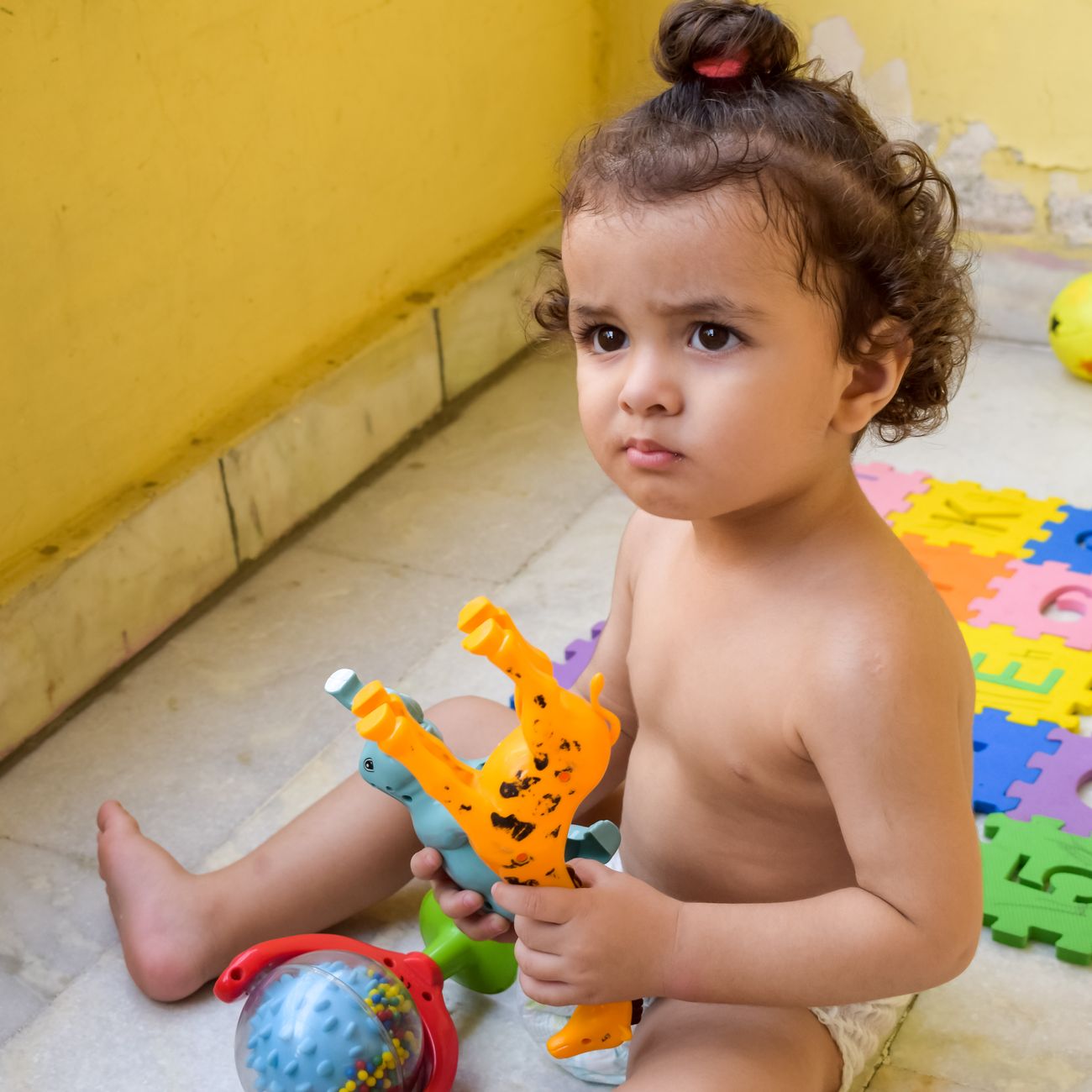 Toddler playing with colorful plastic toys indoors on a sunny morning