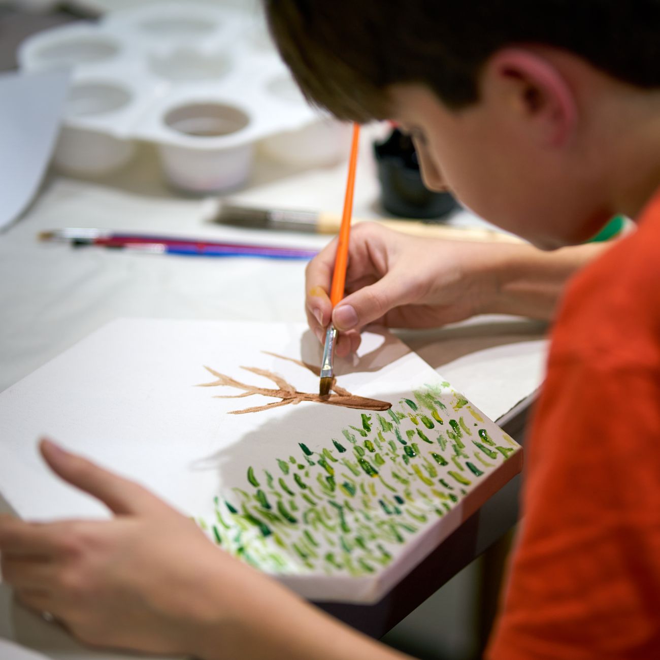 Young child painting a tree on canvas during an art activity